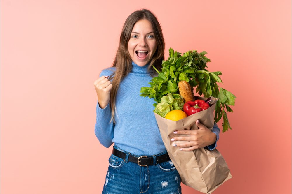 woman holding a grocery shopping bag celebrating a victory in winner position