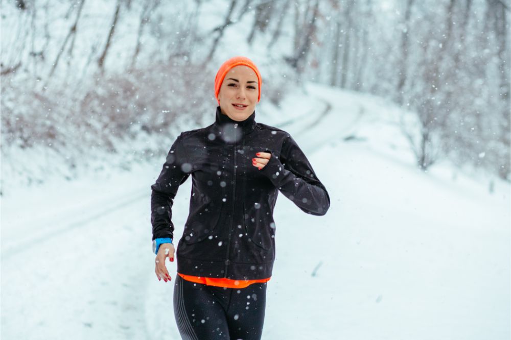 Young woman running in winter park at snowy day.