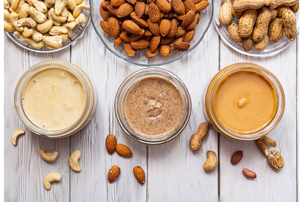  Jars of almond, cashew and peanut butter on a white wooden table