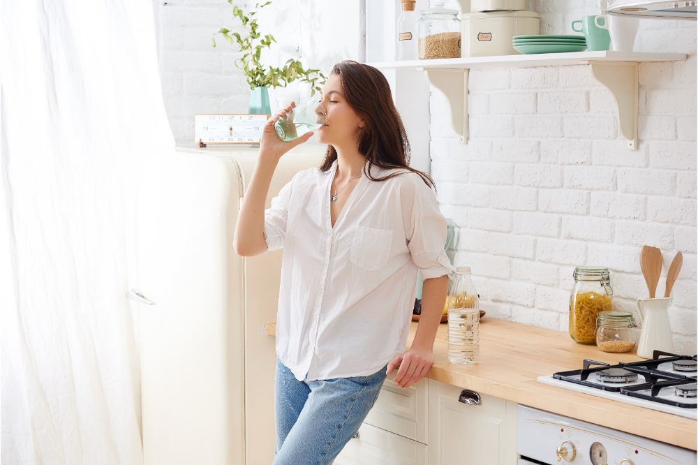 woman drinking water in her kitchen